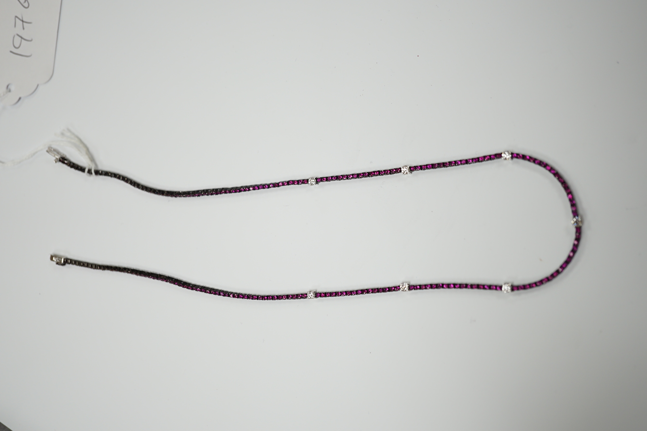 A modern blackened 18k, ruby and diamond line cluster set necklace, 42cm, gross weight 10.3 grams.